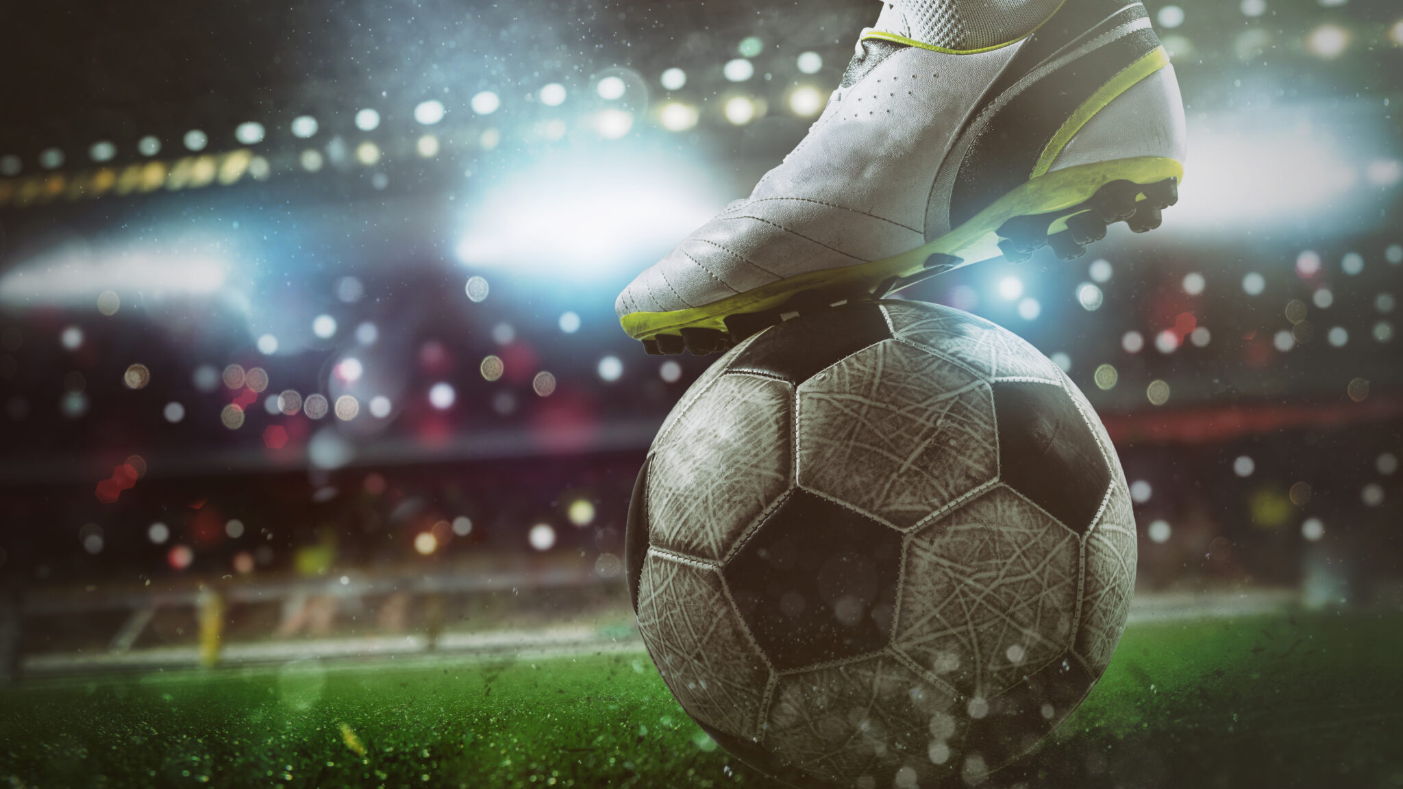 Fußballschuh auf einem Ball im Flutlicht eines Stadions